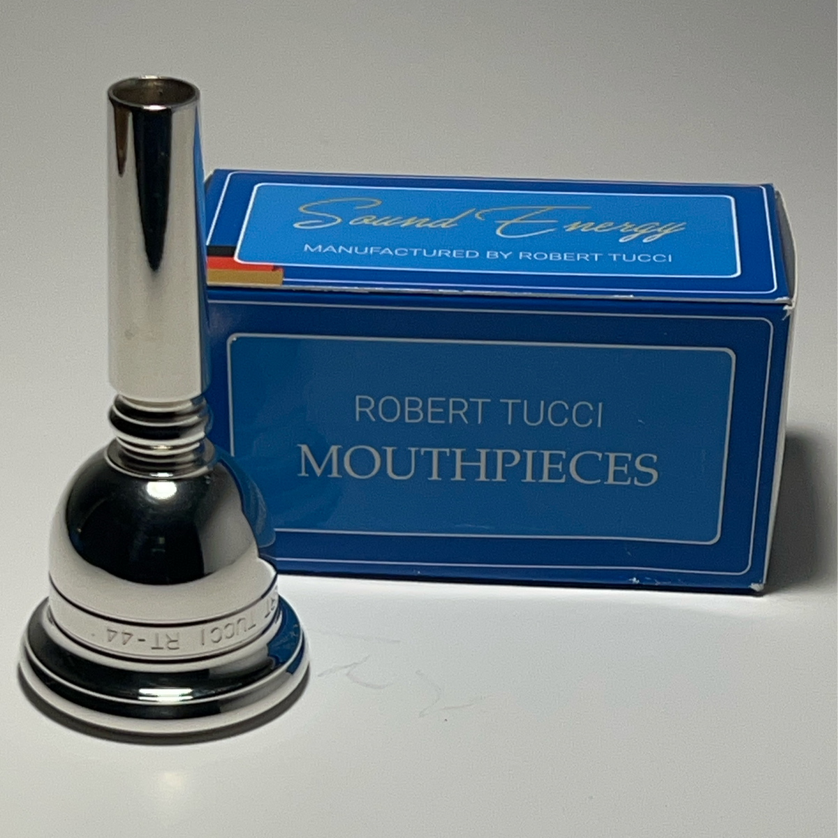 Robert Tucci RT-44 Tuba Mouthpiece with blue box with “Robert Tucci Mouthpieces” printed on it.