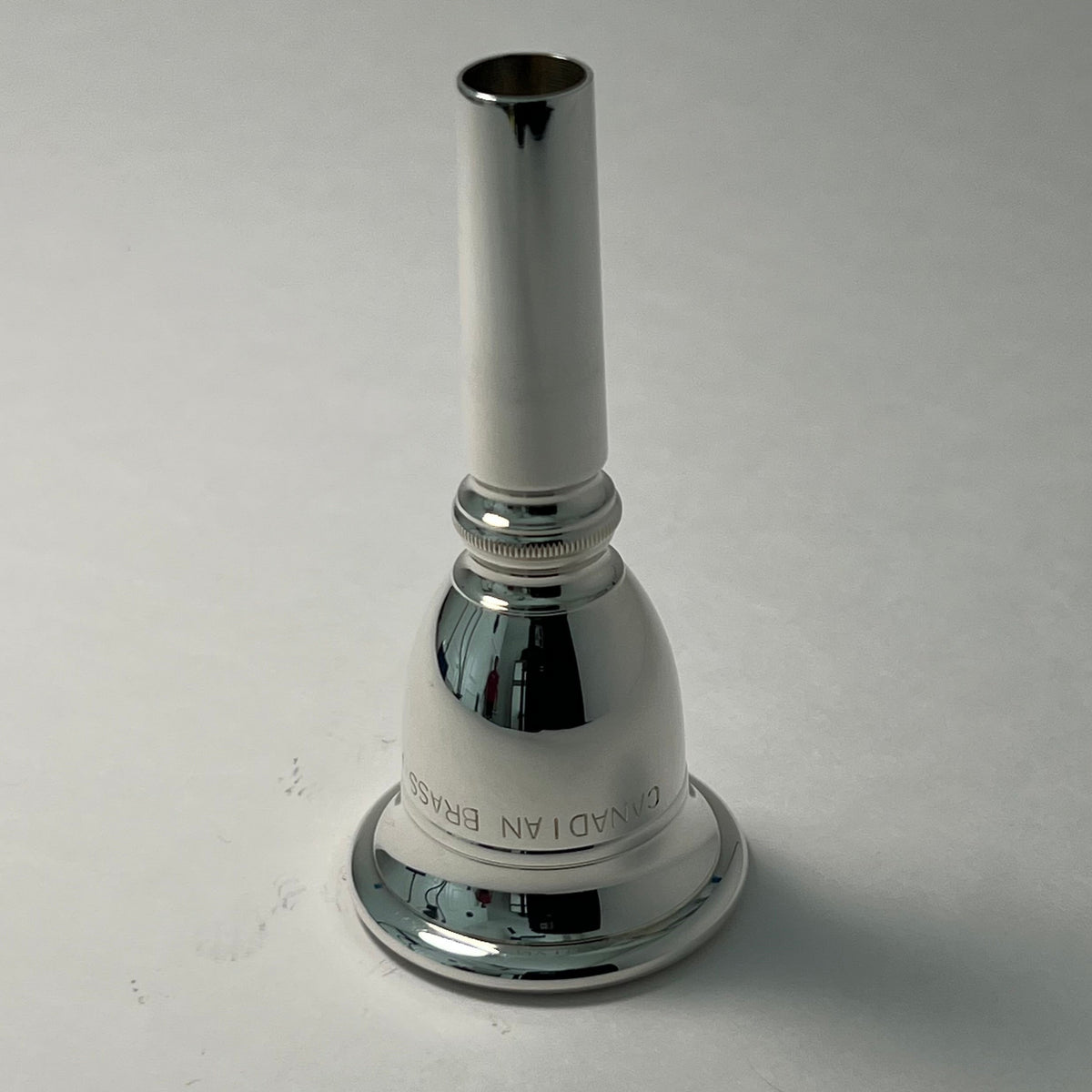 Silver tuba mouthpiece on a light gray background