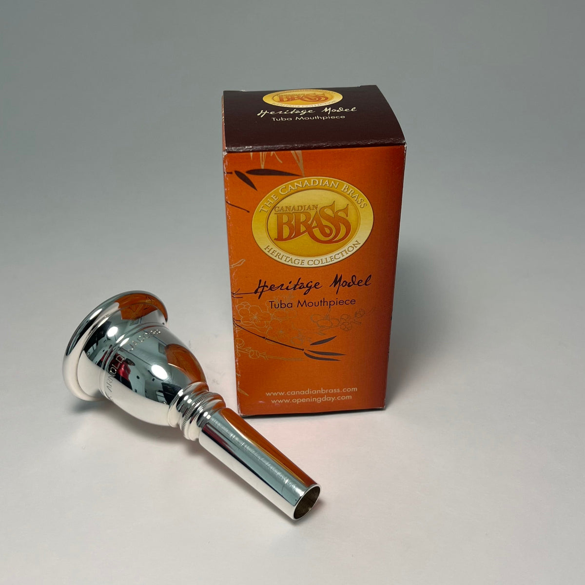 Silver tuba mouthpiece with a brown box labeled 'Bressi' on a gray background