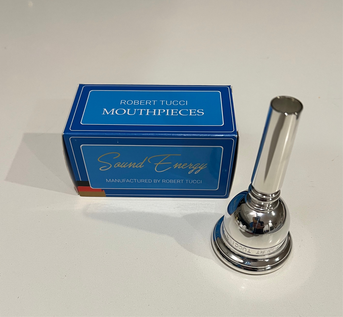 Silver tuba mouthpiece with Robert Tucci mouthpieces box on a white background